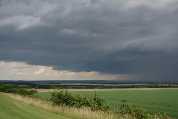 Obraz premium Overcast Sky with Dark Storm Clouds Approaching Over Green Fields and Hills landscape nature