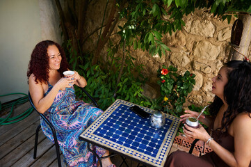Two Women Enjoying Refreshing Drinks Outdoors in a Garden Setting