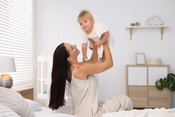 Mother and her cute little baby on bed in room