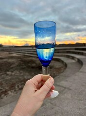 A blue glass of cold wine on a beach sunset sky background in Bajamar, Tenerife, Canary Islands, Spain, celebration