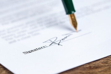 Signing notary document with fountain pen at wooden table, selective focus