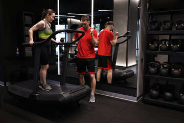 Fototapeta premium Young woman exercising on treadmill with professional personal trainer in gym