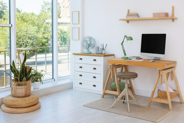 Home workspace. Modern computer and stationery on wooden desk near window indoors