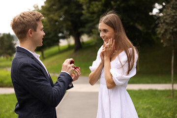 Fototapeta premium Man with engagement ring making marriage proposal to his happy girlfriend outdoors