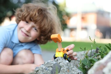 Little boy playing with toy car outdoors, selective focus
