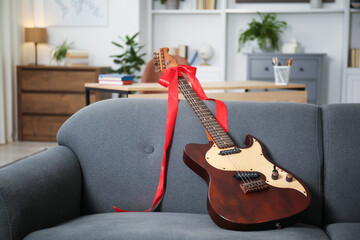 Dreams come true. Guitar with bow on sofa at home, space for text