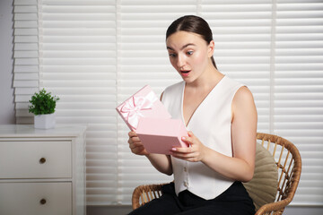 Dreams come true. Excited woman with gift at home