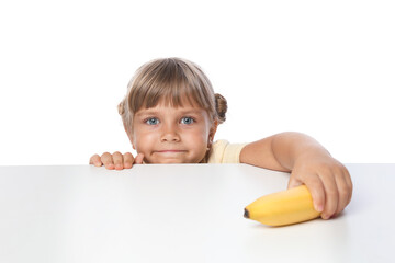 Cute little girl reaching for banana at table against white background
