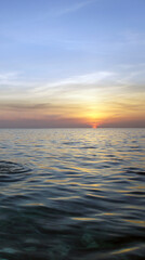 Golden sunset ocean scene with gentle waves and circular ripple under glowing sky