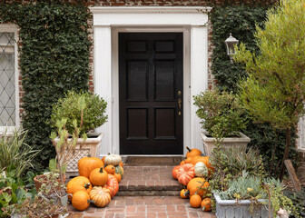 Fall, autumn in beautiful American suburban home with brick stairway entrance, leaves, and variety of pumpkins and gourds arranged artfully as decoration 