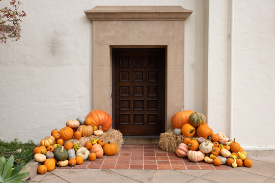 Fall, autumn in beautiful American suburban home with brick stairway entrance, leaves, and variety of pumpkins and gourds arranged artfully as decoration 