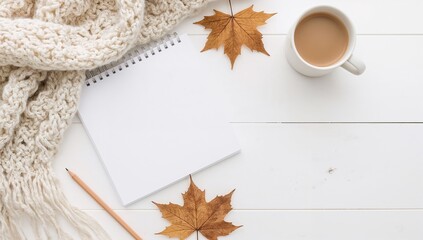 Cozy autumn writing scene: blank notebook, scarf, drink, pencil, leaves, inviting fall inspiration