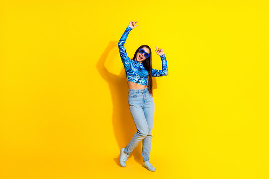 Cheerful young woman dancing in casual outfit against bright yellow backdrop exuding happiness and positive vibes