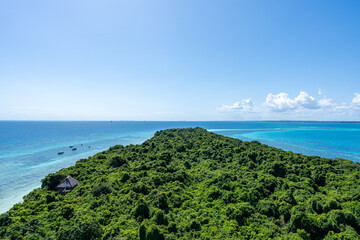A panoramic view of Chumbe Island, Tanzania, with lush green forest surrounded by the turquoise waters of the Indian Ocean.