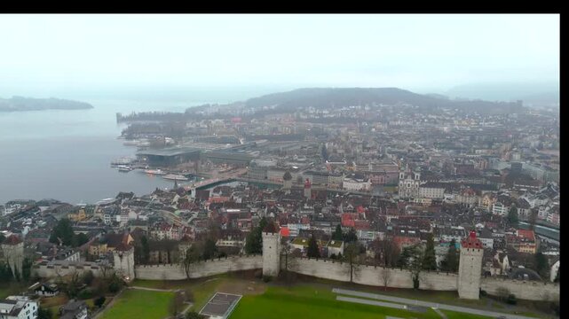 Misty Lucerne from above, showcasing Musegg Wall and towers amidst fog, highlighting the city medieval fortifications and tranquil atmosphere. Luftaufnahme Museggmauer in Luzern, Schweiz. 