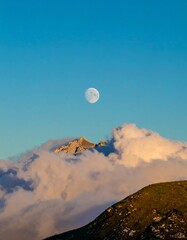 Majestic moon over a mountain range shrouded in clouds