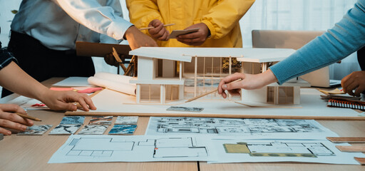 A dynamic scene of a collaborative design process featuring hands engaged with an architectural model and sketches, showcasing creativity and teamwork in a modern workspace. SACTR