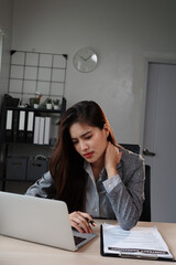 Asian businesswoman suffering from neck pain while working on laptop in office