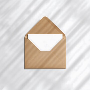 Open kraft envelope with blank invitation card and soft shadows mockup
