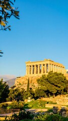 Fototapeta premium Ancient Parthenon temple stands majestically on a hilltop overlooking a lush parkland garden.