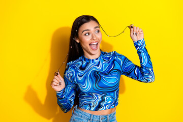Young woman in blue top posing joyfully against a vibrant yellow backdrop expressing vibrant energy...