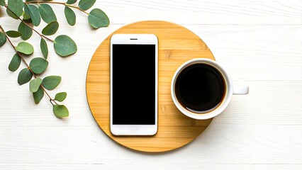 Smartphone and cup of black coffee on wooden tray with green leaves on white table
