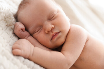 Cute newborn baby sleeping on bed indoors