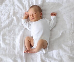 Cute newborn baby sleeping on bed, top view