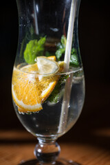 Close-up of orange slices in a glass with a straw against a dark background.

