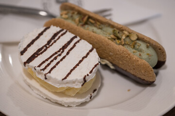 Beautiful delicate meringue cookie and pistachio meringue cookie on a white plate.
