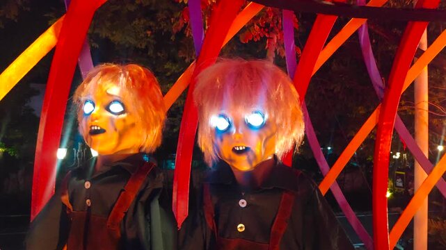 Animatronic demonic twins with glowing eyes in the night. Spooky Halloween decoration.