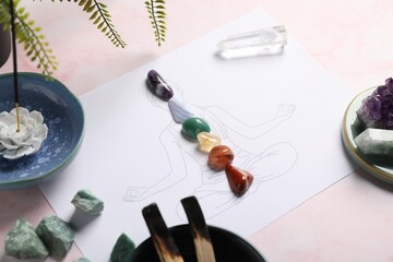 Human drawing with gemstones placed on chakras, incense and palo santo against light background,...
