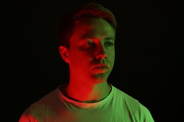 Handsome man in neon lights against black background