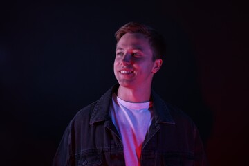 Smiling man in neon lights against black background
