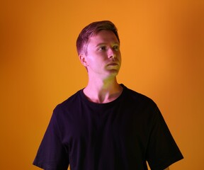 Fototapeta premium Handsome man in neon lights against orange background
