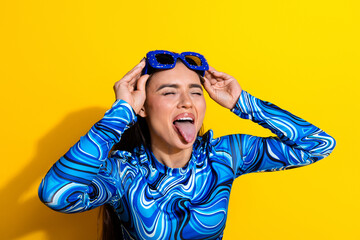 Cheerful Young Woman Posing Playfully in Blue Stylish Top with sunglass Against Bright Yellow...