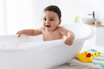 Naklejka premium Cute little baby bathing in tub at home