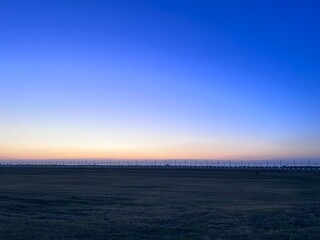 Sunset over golden fields with fence and colorful sky, A golden sunset over a grassy prairie with a rustic wooden fence,  Sunset over a barbed wire fence and rural field, golden light.