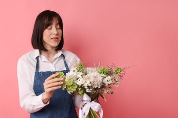 Florist with beautiful bouquet of flowers on pink background, space for text