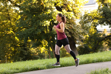 Athletic young woman in sportswear running outdoors