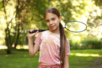 Portrait of smiling little girl with badminton racket in park