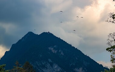 A gathering of paragliders soaring over a mountain peak in Switzerland at sunset