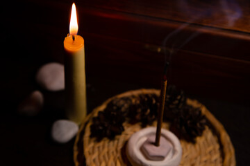 Smoldering aroma incense stick near burning wax candle on decor wood warm background with natural...