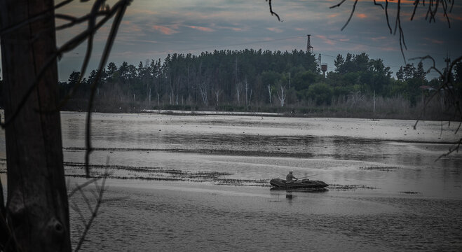 Fisherman in a boat, against the backdrop of an evening forest landscape, beautiful sky before dusk - Powered by Adobe