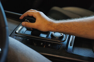 A close-up of a hand reaching for the gear shift in a contemporary vehicle, showcasing the...
