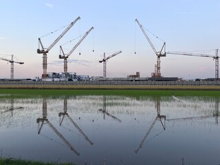 construction tower crane isolated on blue sky with white clouds background,Construction Cranes at Dawn. Construction tower cranes on a farm site. 