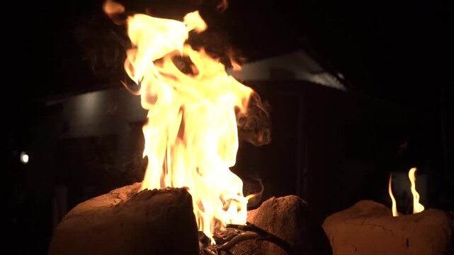 Closeup shot of wood logs burning in earthen stove. Outdoor traditional cooking.