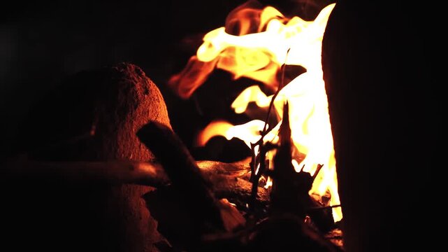 Closeup shot of wood logs burning in earthen stove. Outdoor traditional cooking.