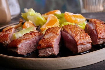 Sliced seared duck breast with salad and orange sauce.