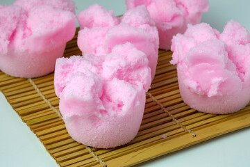 A close-up of a vibrant pink Kue Mangkok or Huat Kueh, a traditional steamed sponge cake from...